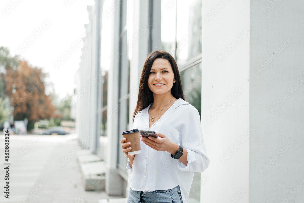 Street portrait of a young woman with a phone in her hand and a coffee to go Street portrait of a young woman with a phone in her hand and a coffee to go