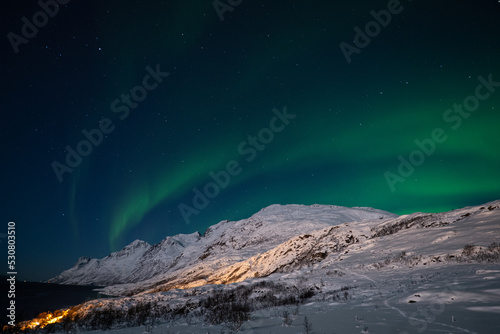 snowy mountain landscape and aurora borealis Tromso Norway