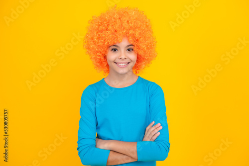 Happy teenager portrait. Teenage girl with yellow wig. Funny child wearing orange curly wig hair. Smiling girl.
