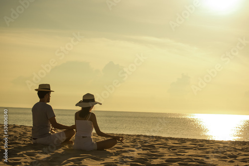 Young asian couple doing yoga exercises on the beach. lifestyle concept © ic36006
