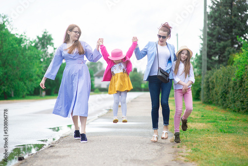 Group of happy family people -two sisters and little girls walking down the city street on a sunny summer day
