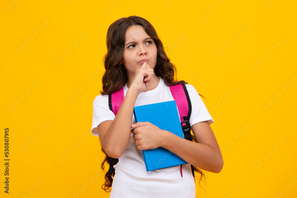 Thinking pensive clever teenager girl. Back to school. Schoolgirl student with school bag backpack hold book on isolated studio background. School and education concept. Thinking pensive clever teenager girl. Back to school. Schoolgirl student with school bag backpack hold book on isolated studio background. School and education concept.