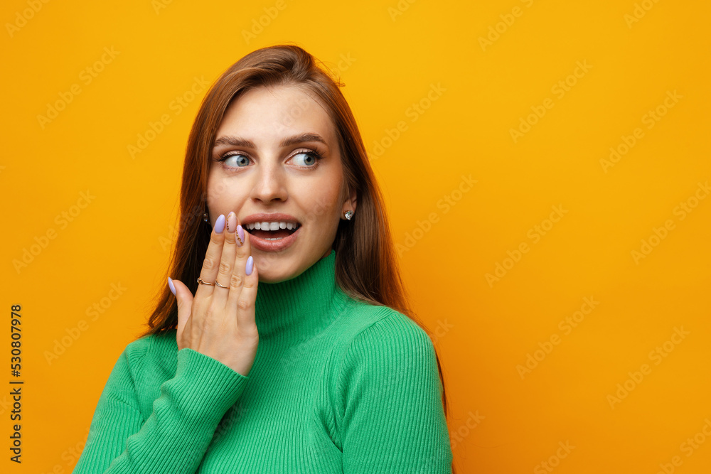 Photo of beautiful woman holding hands near mouth against yellow background