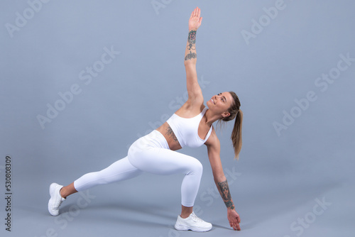 Full body of young cheerful smiling woman in sports wear, isolated over gray background. Healthy beautiful sportswoman.
