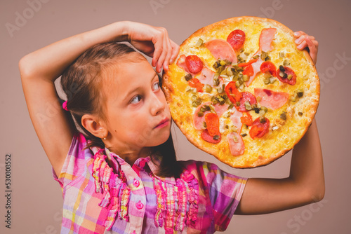 Concept of fast food, pizzeria. Young cheerful girl having fun with slize of pizza. Copy space for design photo