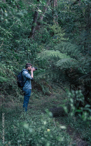 Caucasian photographer taking photos in the middle of the forest