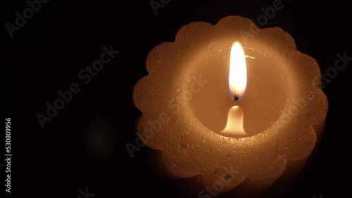 a burning candle on a black background on the side