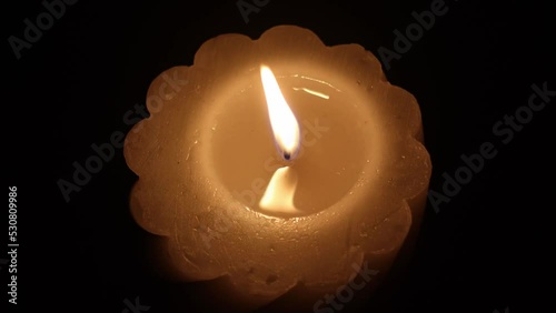 a burning candle on a black background in the center