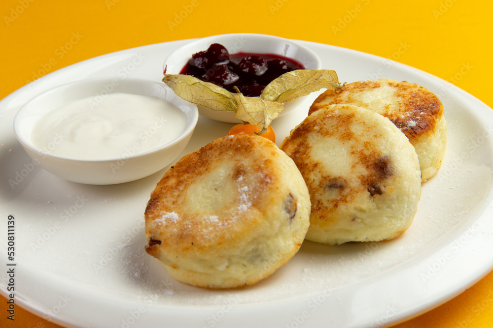 Traditional breakfast syrniki in a plate on a yellow background. Traditional breakfast syrniki in a plate on a yellow background.