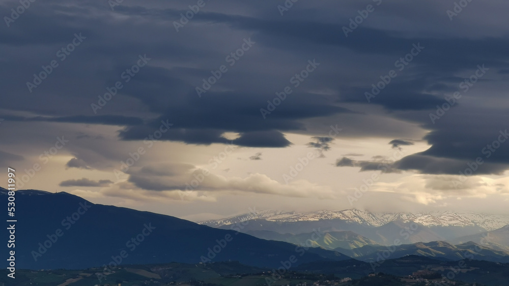 Nuvole bianche e nuvole nere tempestose sopra le montagne le colline e le valli