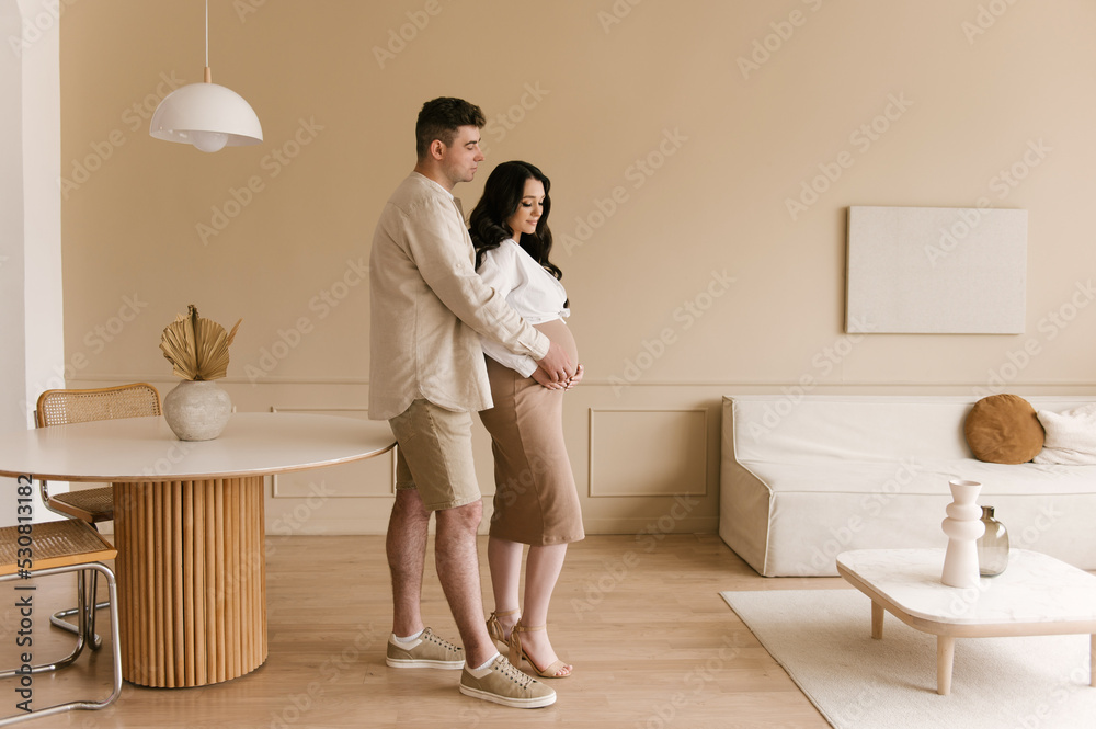 Young pregnant woman with husband at home, happy family and pregnancy concept