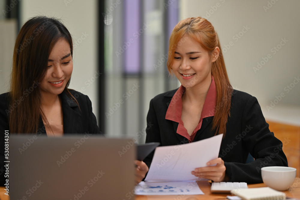 Two of Asian businesswomen working with a document and laptop. Two of Asian businesswomen working with a document and laptop.