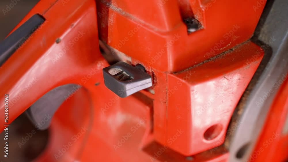Smooth camera movement around an old orange chainsaw close-up. Button lever for opening and closing the air damper for adjusting the air-fuel mixture during a cold start of the engine Smooth camera movement around an old orange chainsaw close-up. Button lever for opening and closing the air damper for adjusting the air-fuel mixture during a cold start of the engine