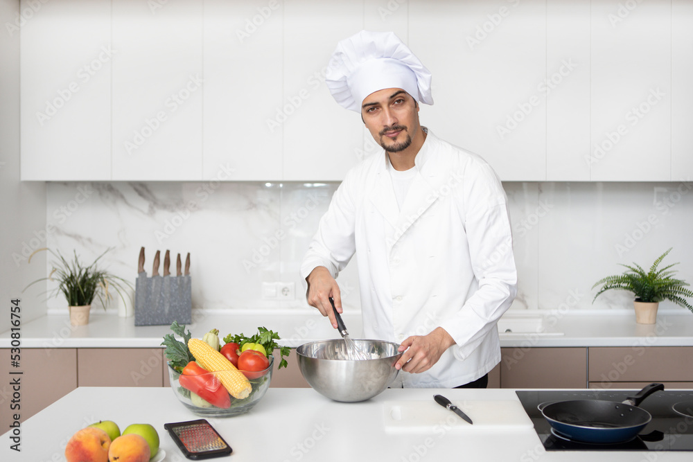 Young handsome male chef is cooking in the kitchen Young handsome male chef is cooking in the kitchen