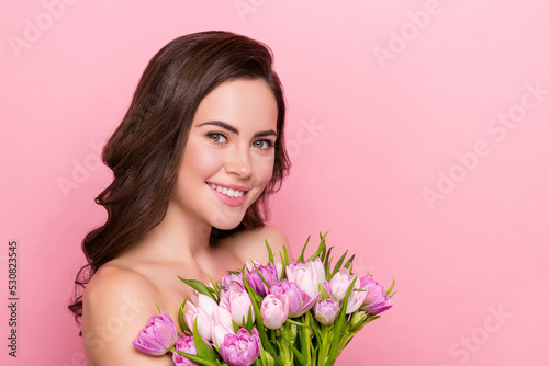 Photo of dreamy adorable young woman naked shoulders holding flowers blossom empty space isolated pink color background