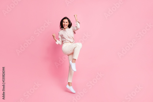Full size photo of cheerful lady jump fists up celebrate award isolated on pastel color background