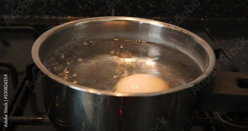 boiling water in a kitchen and putting egg 