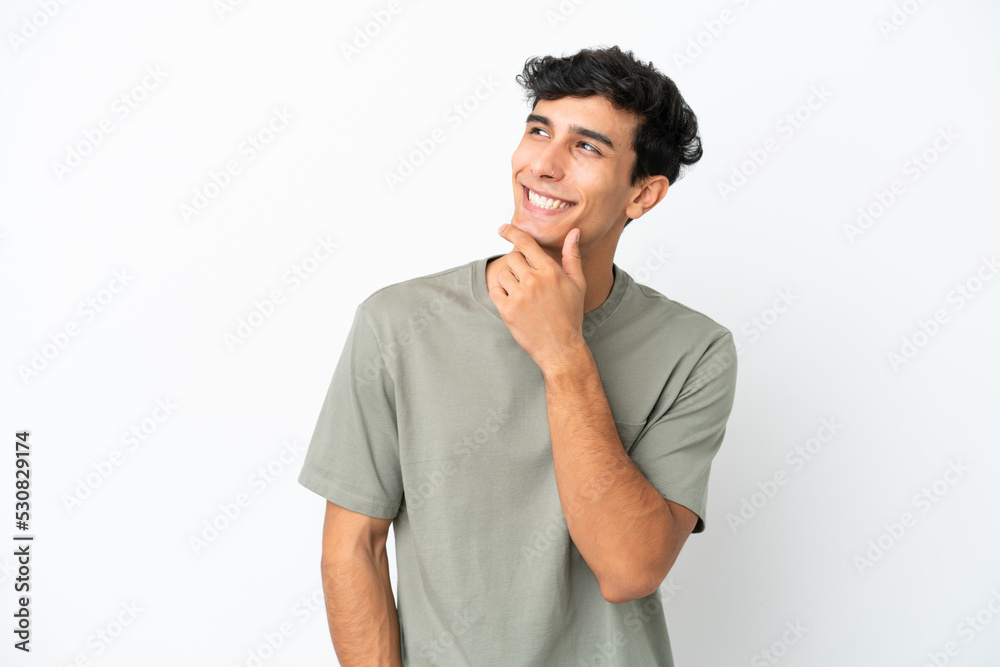 Young Argentinian man isolated on white background looking up while smiling Young Argentinian man isolated on white background looking up while smiling