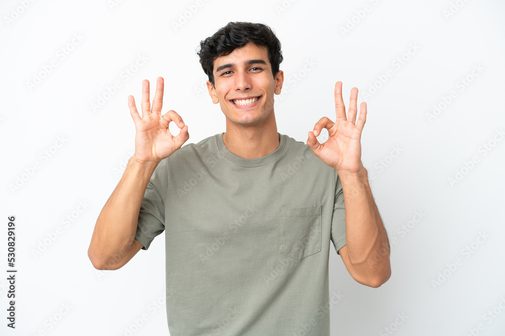 Young Argentinian man isolated on white background showing ok sign with two hands Young Argentinian man isolated on white background showing ok sign with two hands