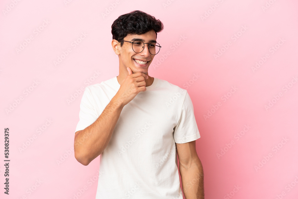 Young Argentinian man isolated on pink background looking to the side and smiling Young Argentinian man isolated on pink background looking to the side and smiling