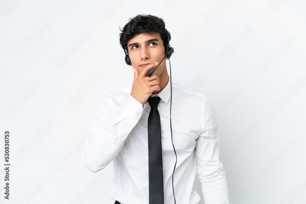 Telemarketer man working with a headset isolated on white background having doubts and with confuse face expression Telemarketer man working with a headset isolated on white background having doubts and with confuse face expression