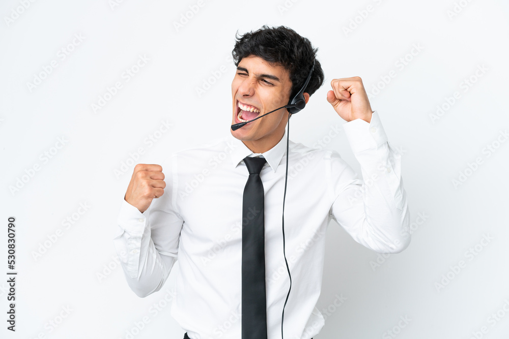 Telemarketer man working with a headset isolated on white background celebrating a victory