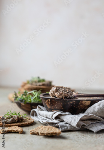 Homemade meat or chicken liver pate with multigrain crackers and microgreen, light concrete background.