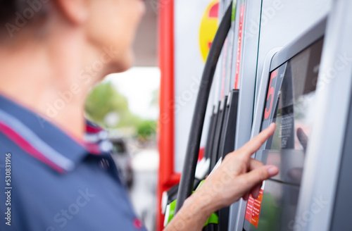 Woman at self-service fuel pump in European gas station types on the display the required amount - inflation, price increase, economy, speculation concept photo