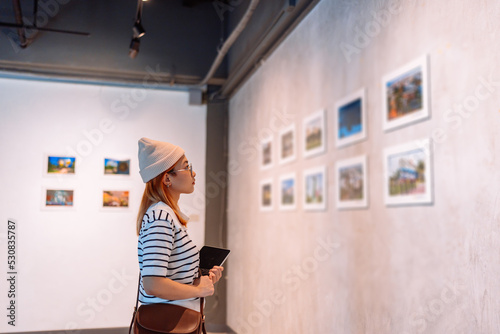 Woman visiting art gallery her looking pictures on wall watching photo frame painting at artwork museum people lifestyle concept.