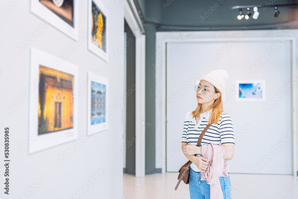 Woman visiting art gallery her looking pictures on wall watching photo frame painting at artwork museum people lifestyle concept. - obrazy, fototapety, plakaty 