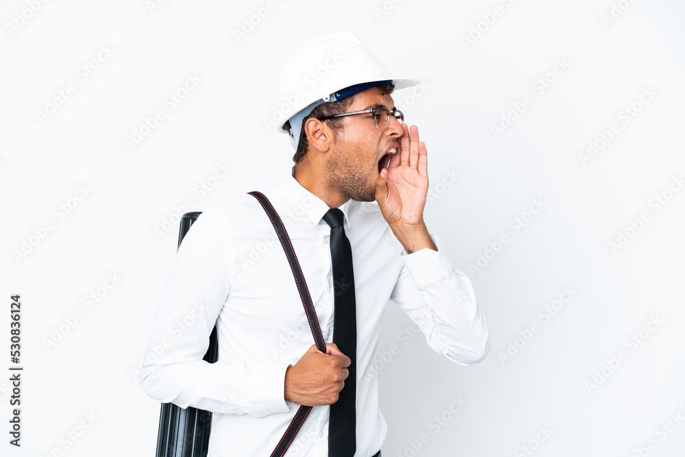 Architect brazilian man with helmet and holding blueprints shouting with mouth wide open to the side Architect brazilian man with helmet and holding blueprints shouting with mouth wide open to the side