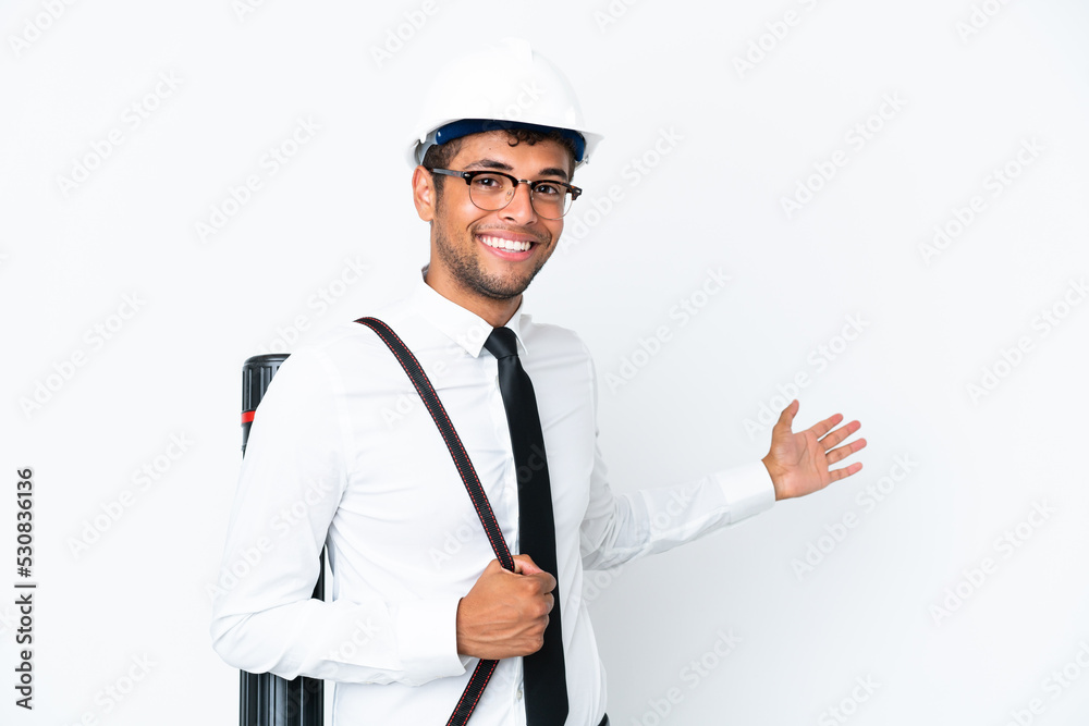 Architect brazilian man with helmet and holding blueprints extending hands to the side for inviting to come Architect brazilian man with helmet and holding blueprints extending hands to the side for inviting to come
