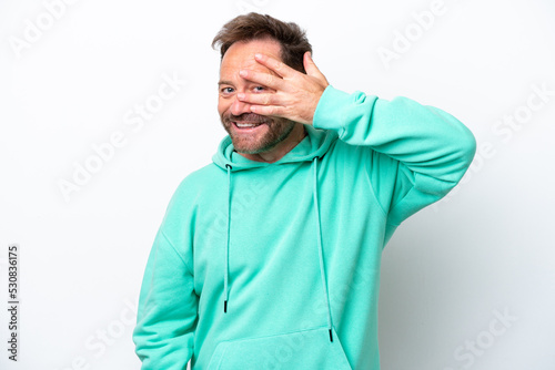 Middle age caucasian man isolated on white background covering eyes by hands and smiling © luismolinero