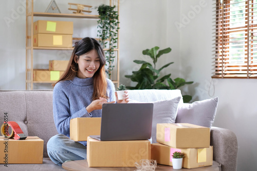Starting Small business entrepreneur freelance, Portrait young woman working at home office, BOX, smartphone, laptop, online, marketing, packaging, delivery, b2b, SME, e-commerce concept © wichayada