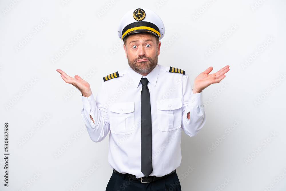 Airplane middle age pilot isolated on white background having doubts while raising hands Airplane middle age pilot isolated on white background having doubts while raising hands