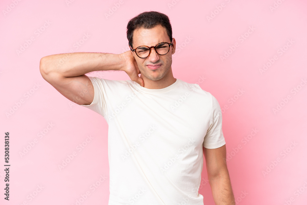 Young caucasian man isolated on pink background with neckache