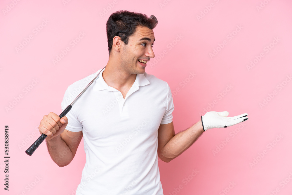 Young golfer player man isolated on pink background with surprise expression while looking side
