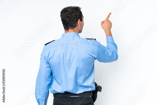 Young police caucasian man isolated on white background pointing back with the index finger