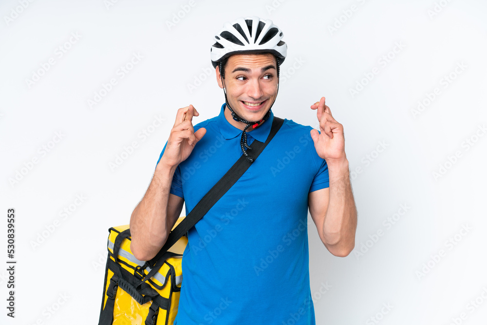 Young caucasian man with thermal backpack isolated on white background with fingers crossing Young caucasian man with thermal backpack isolated on white background with fingers crossing