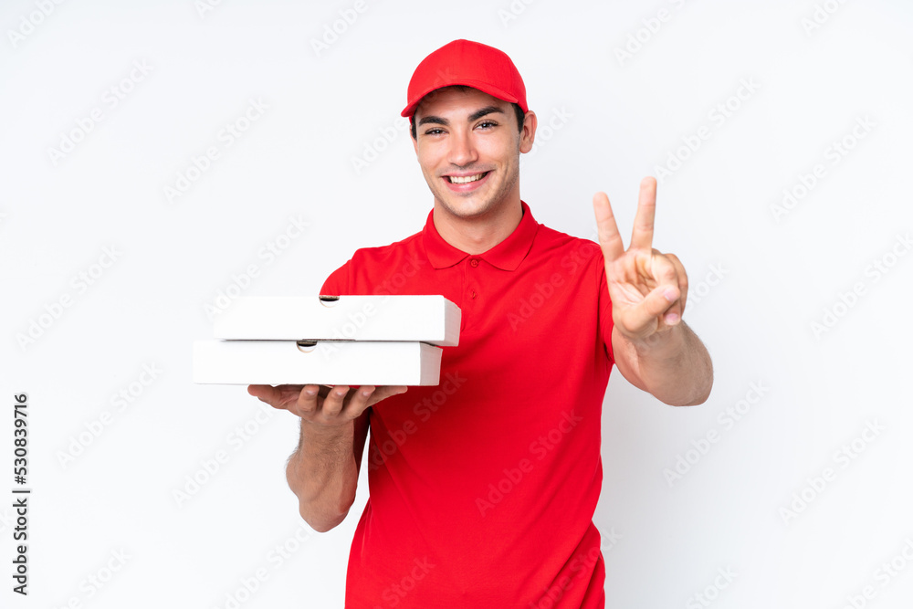 Pizza delivery caucasian man with work uniform picking up pizza boxes isolated on white background smiling and showing victory sign Pizza delivery caucasian man with work uniform picking up pizza boxes isolated on white background smiling and showing victory sign