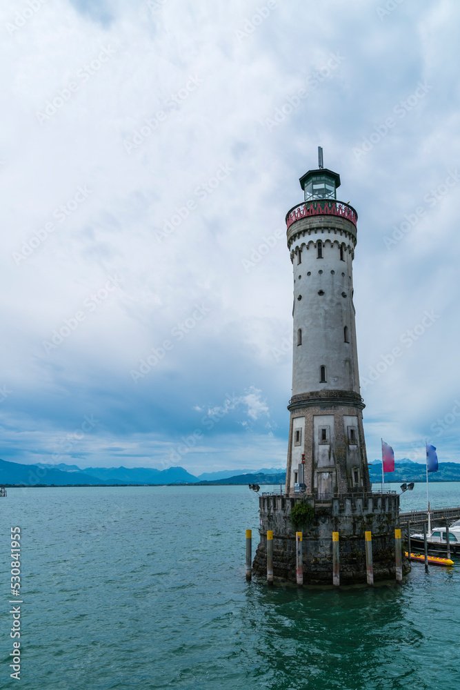 Germany, Lindau lighthouse in ancient port at bodensee lake with view to austrian coastline and switzerland saentis mountain top