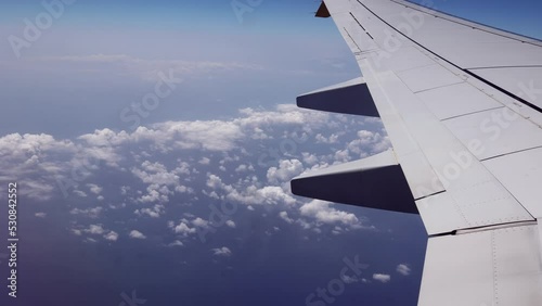 Looking Outside a Window of an Aircraft Cabin: White Airplane Wing and Clouds