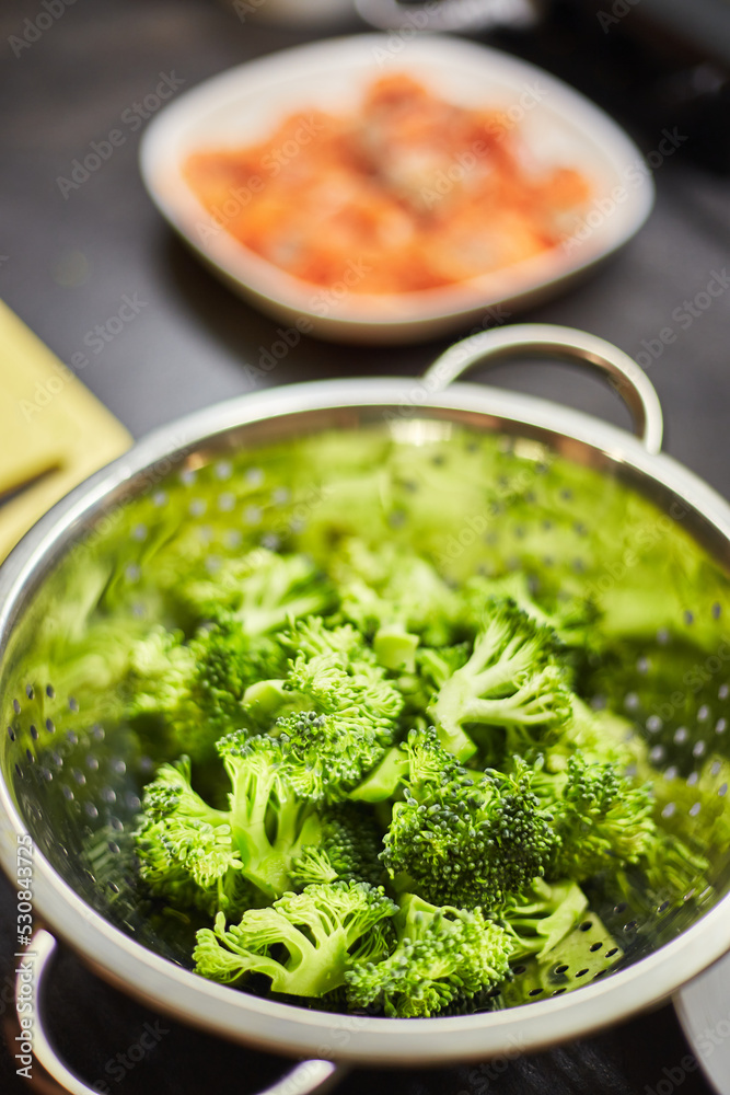 Boiled broccoli in metal colander, close-up