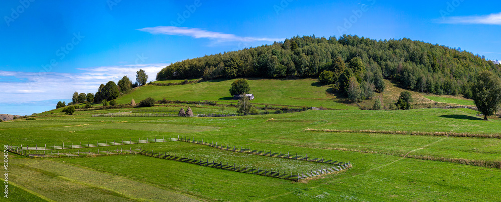 Obraz premium Panoramic landscape of a green field with wooden fence in a rural area
