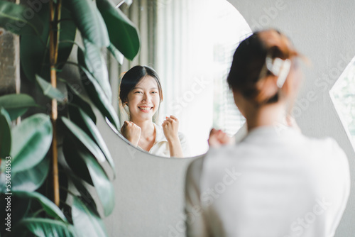 Asian woman looking through the mirror and confident of herself. cheer yourself up photo