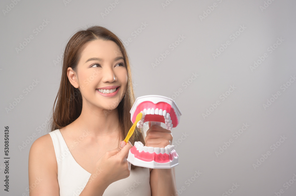 Young smiling woman holding toothbrush over white background studio, dental healthcare and Orthodontic concept.. Young smiling woman holding toothbrush over white background studio, dental healthcare and Orthodontic concept..