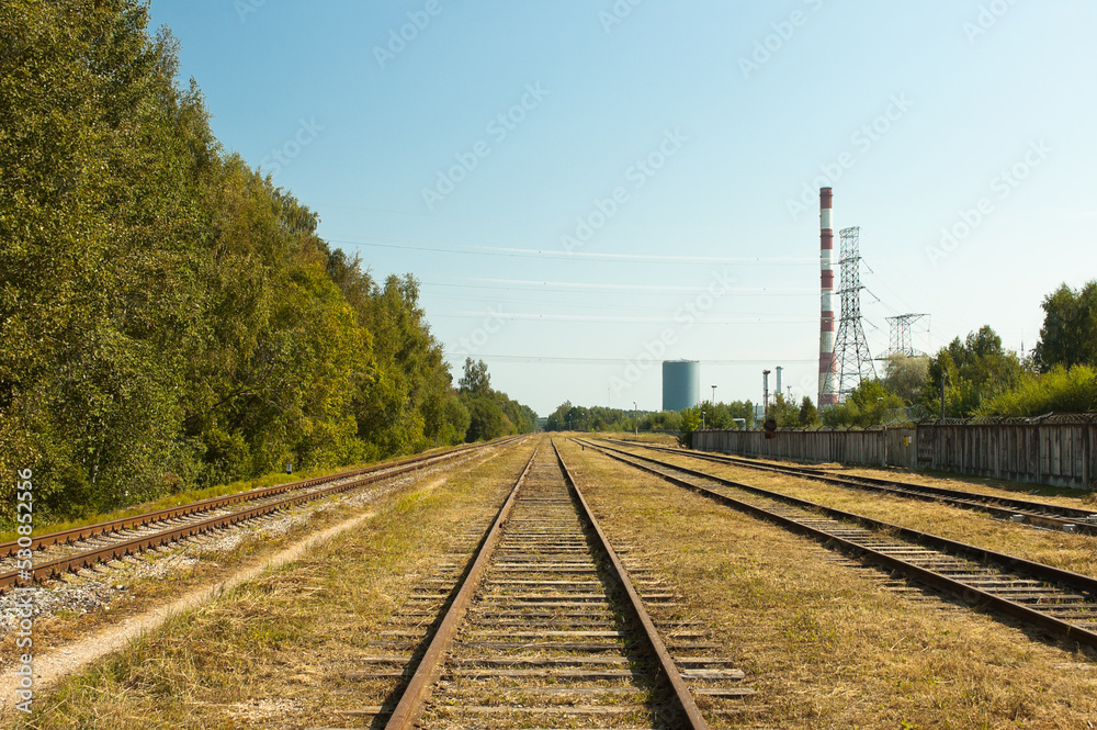 railway, in the photo straight lines of railway tracks in the background of the power plant tower and blue sky