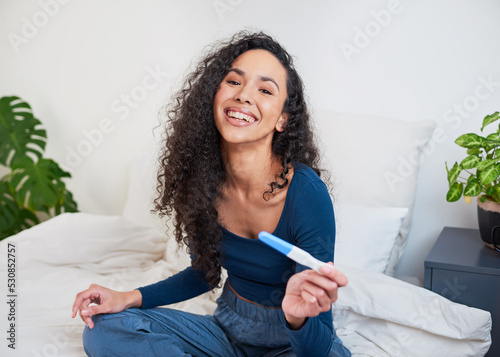 Foto A young happy multi-ethnic woman holds pregnancy test smiling at camera
