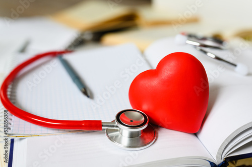 Red heart on books and phonendoscope. Selective focus on heart and phonendoscope. Concept of medical literature
