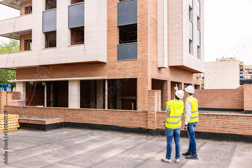 Two professional engineers architect workers discussing at apartment building construction site